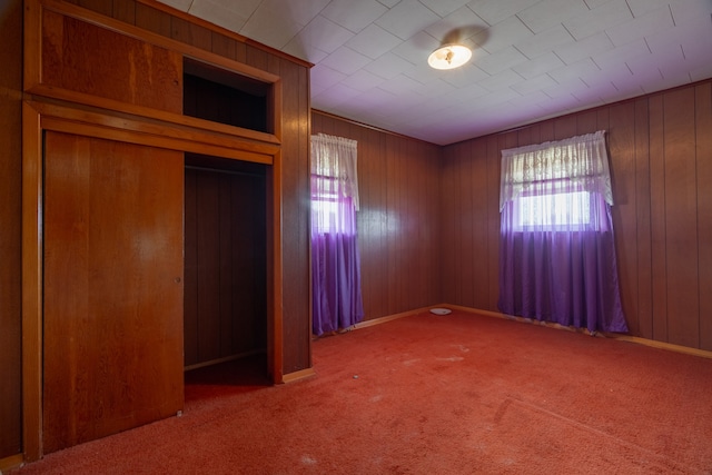 unfurnished bedroom with carpet and wood walls