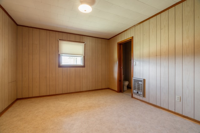 carpeted spare room with crown molding and wood walls