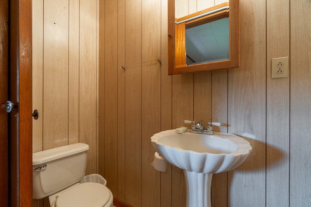 bathroom featuring wooden walls and toilet