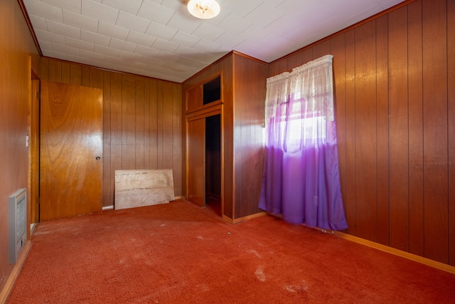 unfurnished room featuring wooden walls and carpet