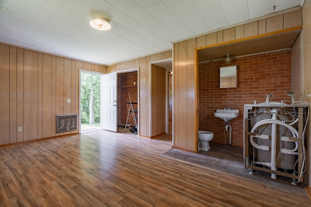 interior space with sink, dark hardwood / wood-style floors, wooden walls, and brick wall