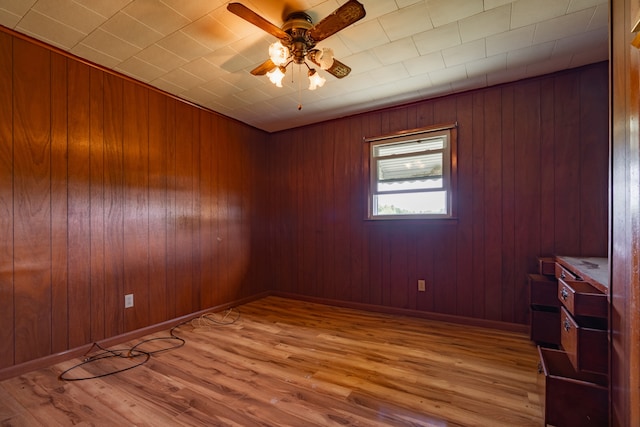 spare room with wood-type flooring, ceiling fan, and wood walls