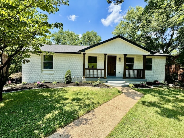 single story home featuring covered porch and a front yard