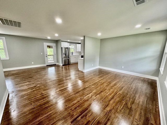 unfurnished living room featuring plenty of natural light and dark hardwood / wood-style floors