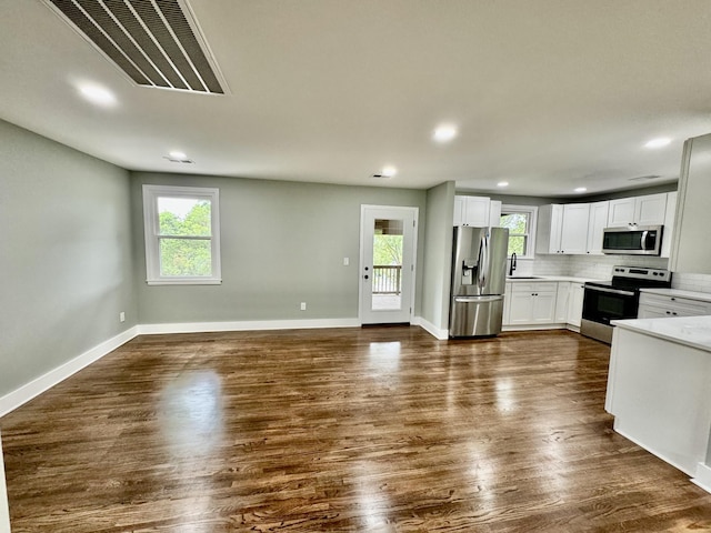 kitchen featuring sink, stainless steel appliances, tasteful backsplash, dark hardwood / wood-style flooring, and white cabinets