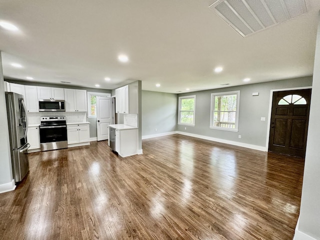 kitchen with backsplash, dark hardwood / wood-style floors, white cabinetry, and stainless steel appliances