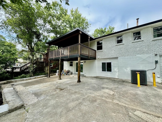 rear view of house with central air condition unit, a wooden deck, and a patio