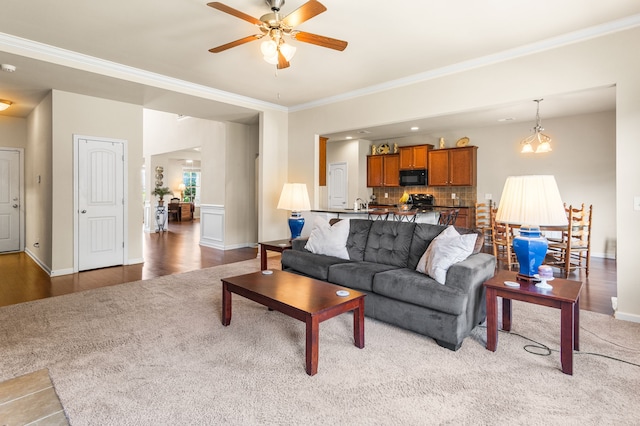 living room featuring hardwood / wood-style floors, crown molding, and ceiling fan