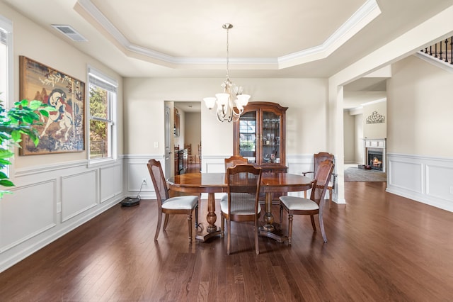 dining area featuring a tray ceiling, dark hardwood / wood-style floors, and an inviting chandelier