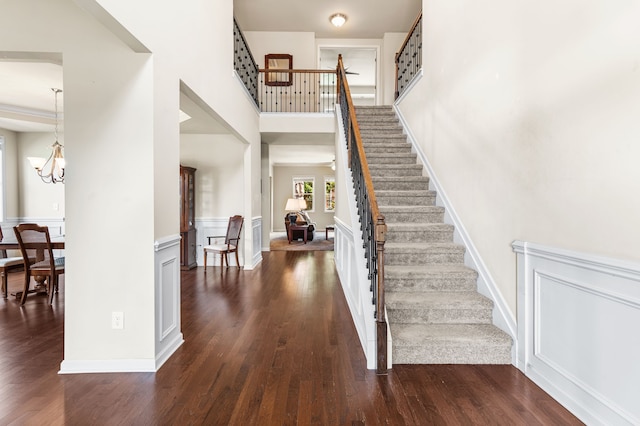 foyer entrance with a high ceiling, dark hardwood / wood-style floors, and an inviting chandelier