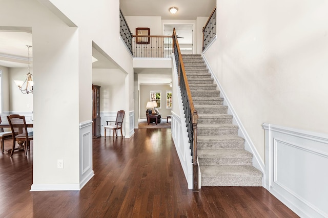 entryway featuring a chandelier, stairway, and dark wood finished floors