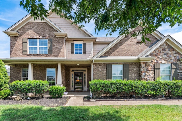 craftsman house with a front yard and brick siding