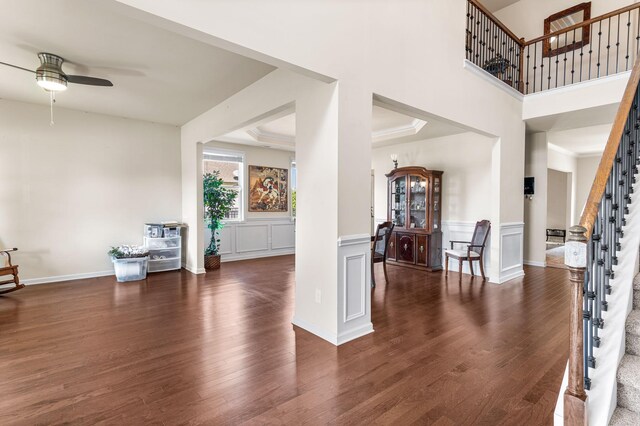 foyer entrance featuring dark wood-style flooring, ceiling fan, stairway, and a decorative wall