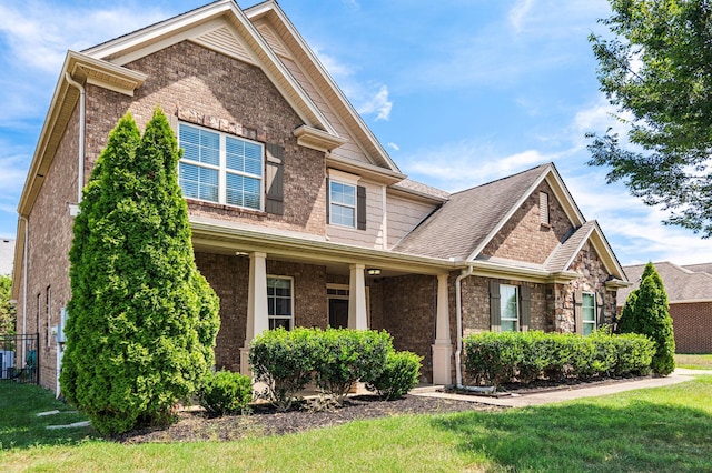 craftsman-style house featuring brick siding, a front lawn, and roof with shingles