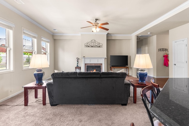 carpeted living area with baseboards, crown molding, a tiled fireplace, and ceiling fan