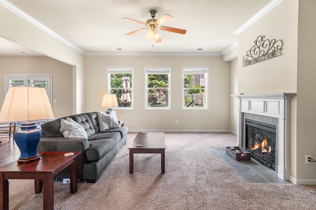 living room with a tile fireplace, crown molding, carpet floors, and ceiling fan