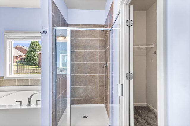 full bath featuring a garden tub, a shower stall, baseboards, and a spacious closet