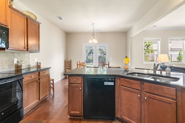 kitchen with dark wood-type flooring, hanging light fixtures, sink, tasteful backsplash, and black appliances