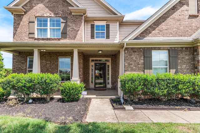 entrance to property with a porch and brick siding