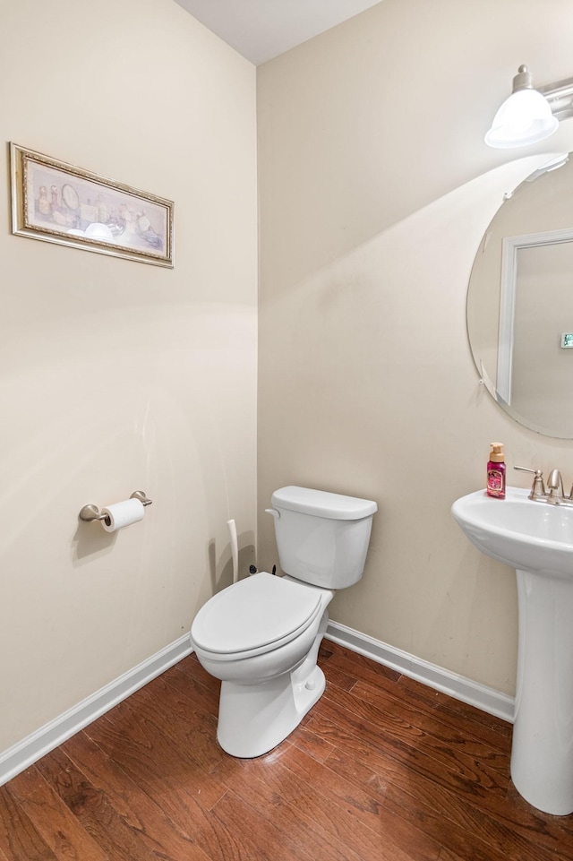 bathroom with toilet, a sink, baseboards, and wood finished floors