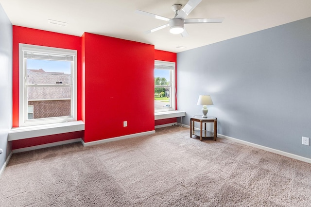 empty room with carpet flooring, a ceiling fan, and baseboards