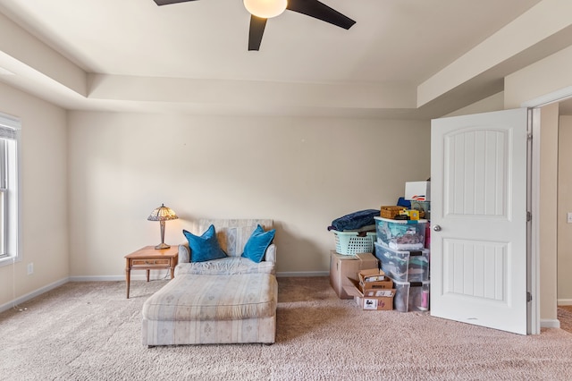 sitting room featuring ceiling fan, a raised ceiling, and light colored carpet