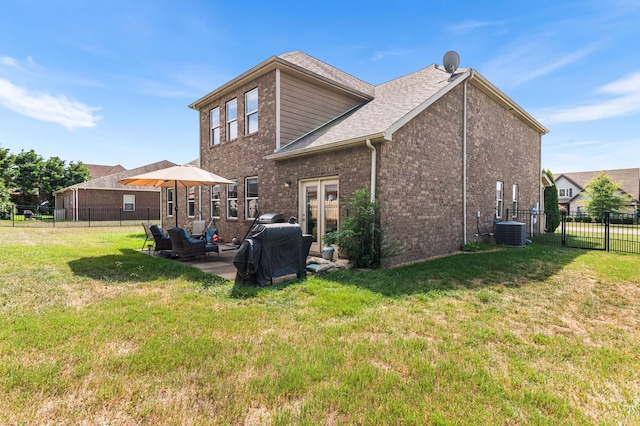 rear view of property featuring cooling unit, a fenced backyard, a lawn, and brick siding