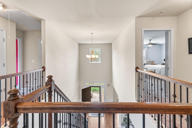 hallway featuring an inviting chandelier, attic access, and an upstairs landing