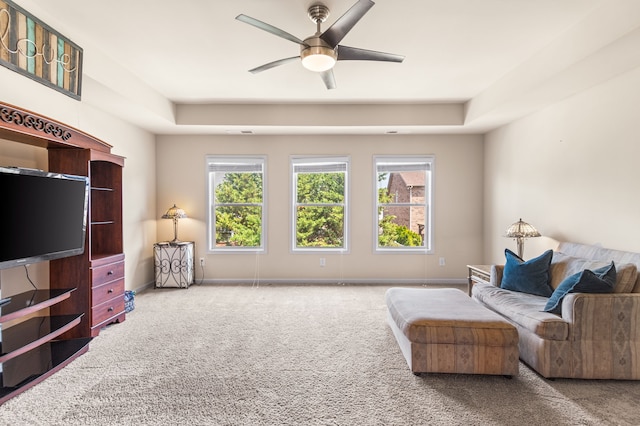 sitting room with ceiling fan, a tray ceiling, and carpet floors