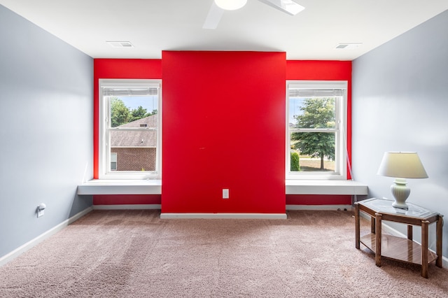 carpeted spare room with ceiling fan and plenty of natural light