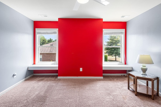 carpeted spare room with baseboards, visible vents, and a ceiling fan