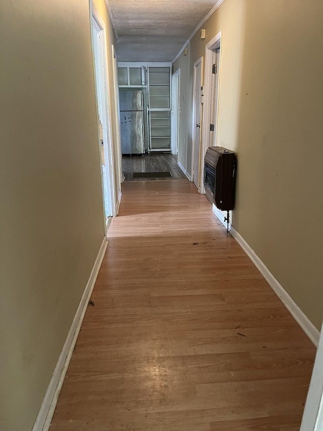 hall featuring heating unit, crown molding, light hardwood / wood-style flooring, and a textured ceiling