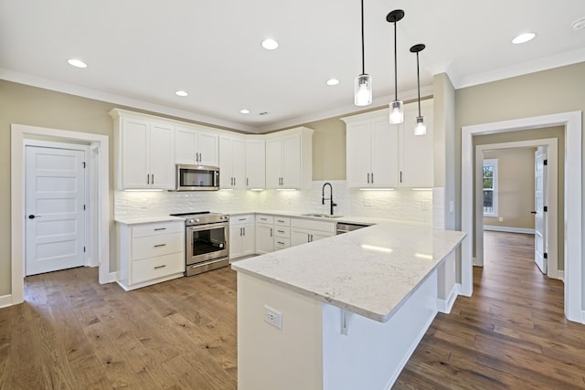 kitchen with white cabinetry, appliances with stainless steel finishes, hardwood / wood-style flooring, pendant lighting, and tasteful backsplash