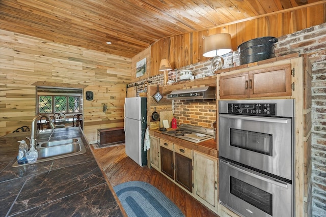 kitchen with white appliances, wooden ceiling, wood walls, and sink