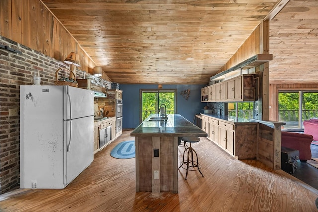 kitchen with a kitchen breakfast bar, sink, light hardwood / wood-style flooring, white fridge, and lofted ceiling