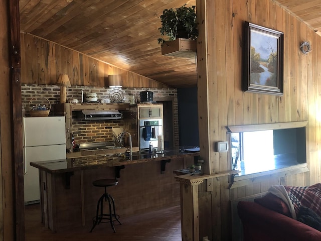 bar featuring wood walls, stainless steel oven, lofted ceiling, white refrigerator, and dark hardwood / wood-style flooring