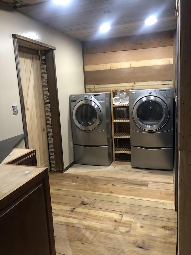 laundry room with washing machine and dryer and light wood-type flooring