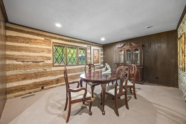 dining room with a textured ceiling and wooden walls