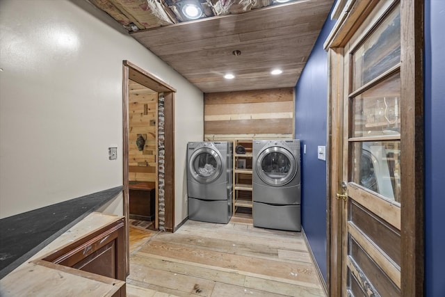 clothes washing area with washer and clothes dryer, light wood-type flooring, and wood ceiling