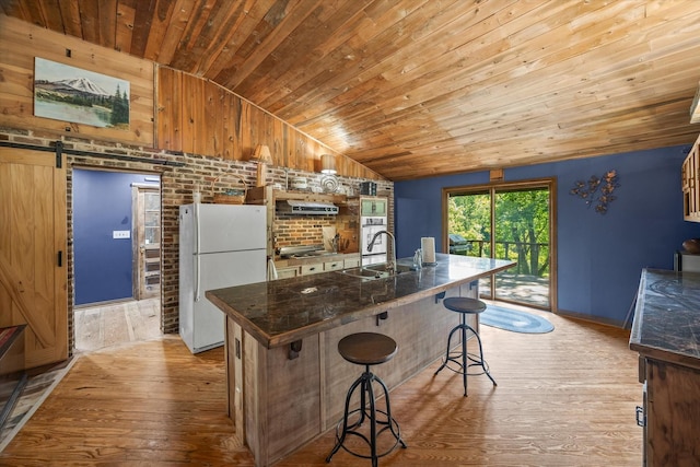 kitchen with sink, a kitchen breakfast bar, a barn door, light hardwood / wood-style floors, and white appliances