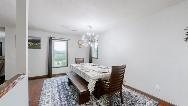 dining space with dark wood-type flooring and an inviting chandelier