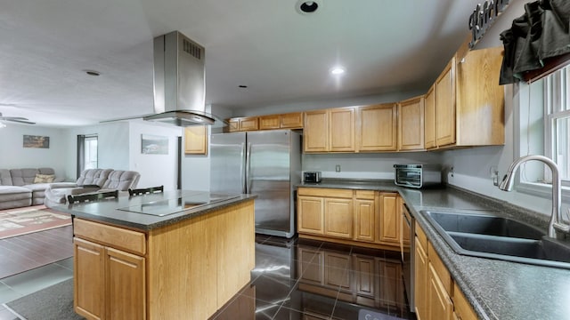 kitchen featuring a center island, wall chimney range hood, sink, ceiling fan, and stainless steel appliances