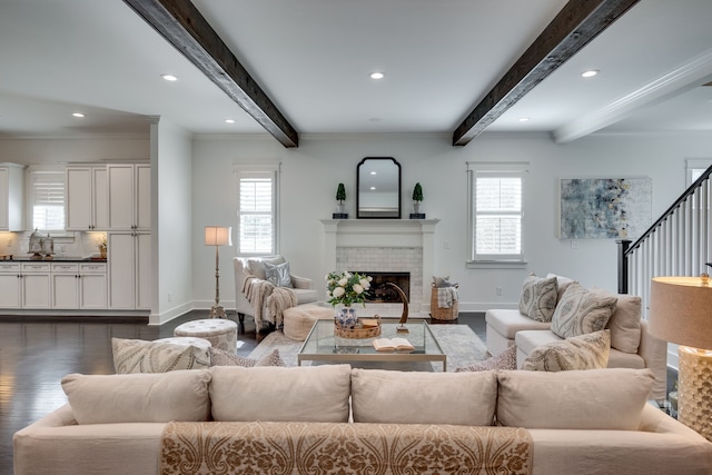 living room featuring beamed ceiling, ornamental molding, dark wood-type flooring, and a fireplace