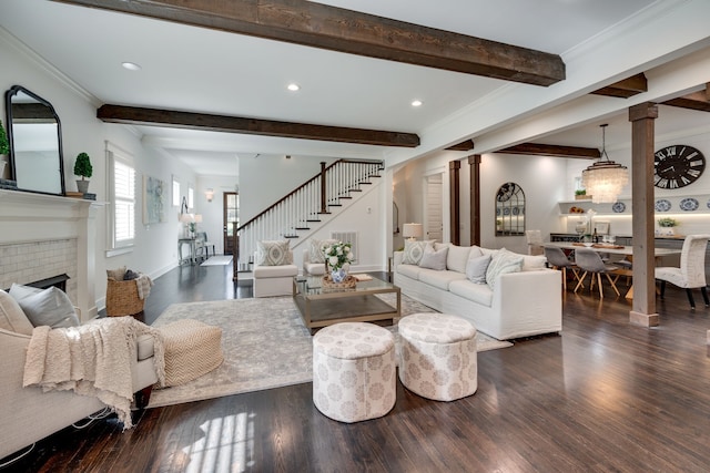 living room with a brick fireplace, beamed ceiling, ornamental molding, and dark wood-type flooring