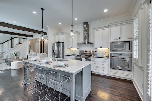 kitchen with stainless steel appliances, dark hardwood / wood-style flooring, wall chimney exhaust hood, a kitchen island with sink, and sink