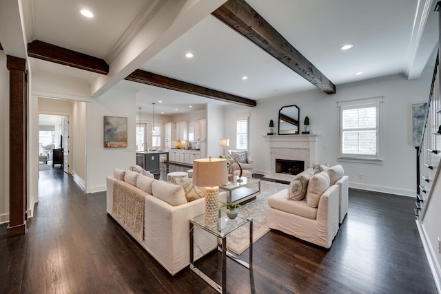 living room featuring a brick fireplace, plenty of natural light, beam ceiling, and dark wood-type flooring