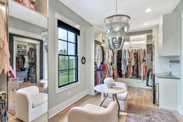 walk in closet with a notable chandelier and light wood-type flooring