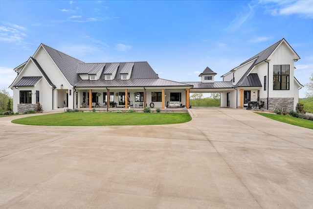 modern farmhouse with a front yard, a carport, and covered porch