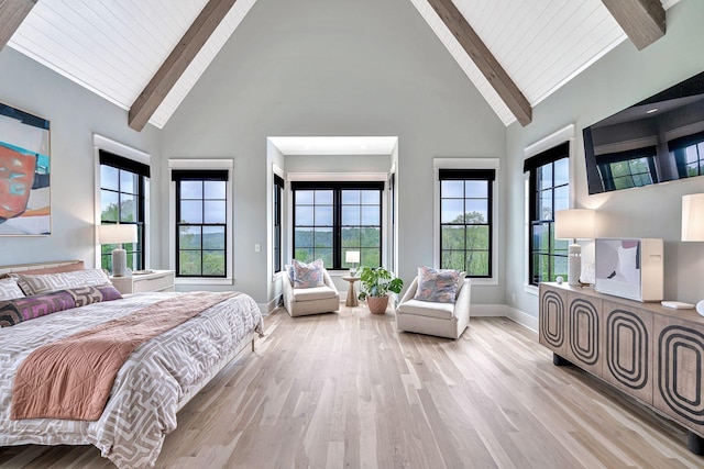 bedroom featuring multiple windows, a towering ceiling, and light wood-type flooring