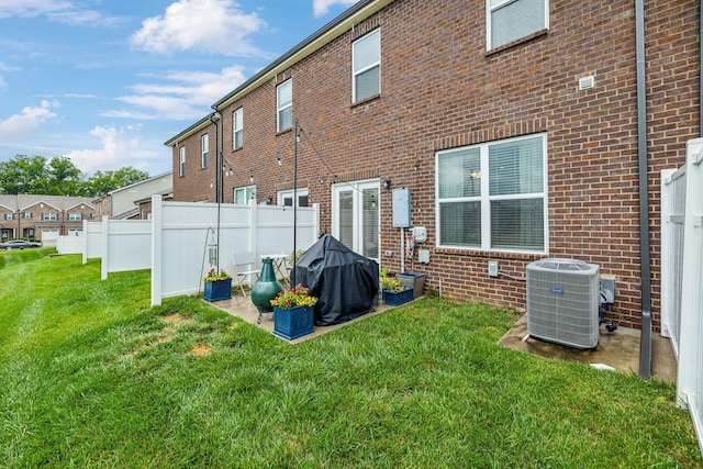 rear view of property featuring central air condition unit and a yard